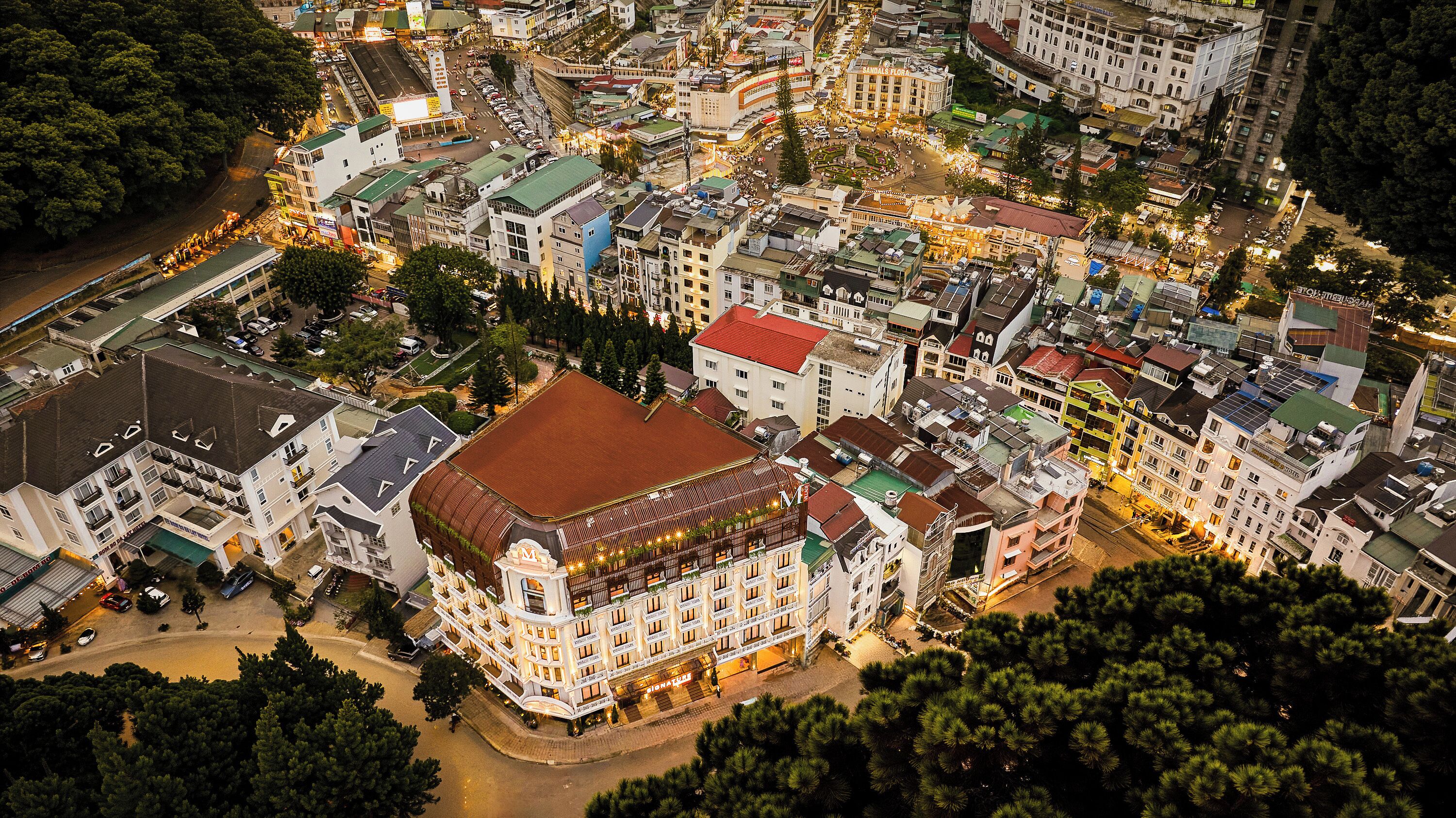 A multi-story hotel with a central courtyard, surrounded by other buildings.