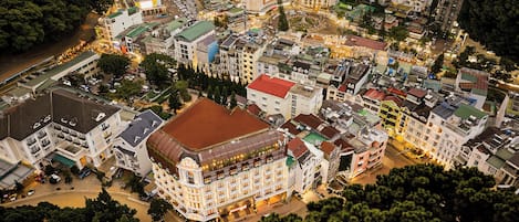 A multi-story hotel with a central courtyard, surrounded by other buildings.