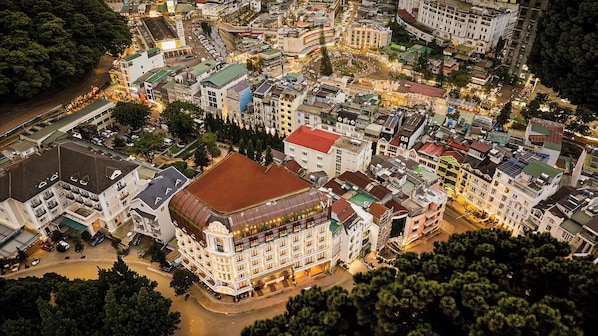 A multi-story hotel with a central courtyard, surrounded by other buildings.