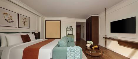 Una habitación de hotel con cama, sofá, televisor y una pequeña mesa con un florero.