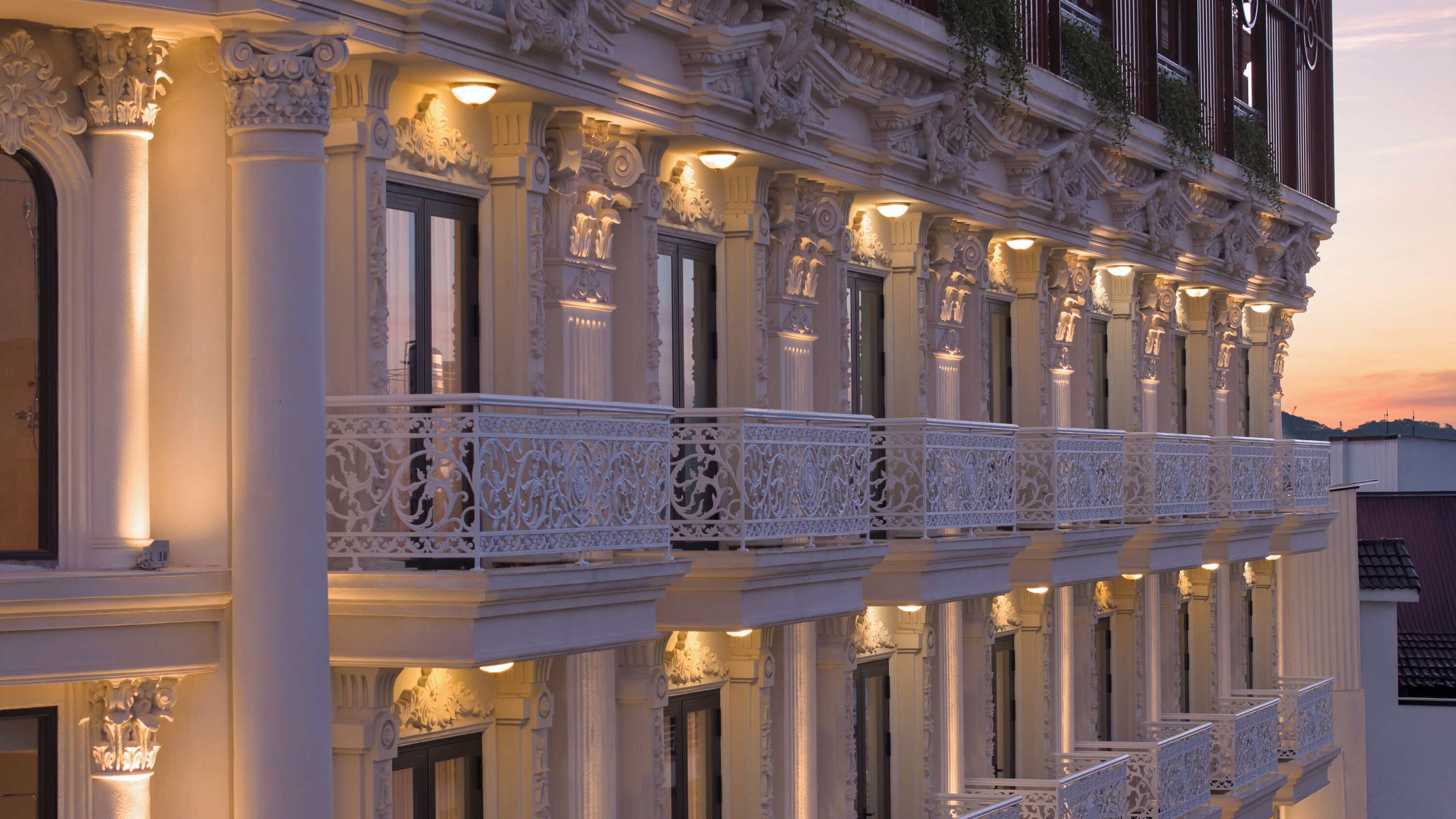 Un edificio con columnas ornamentales y balcones, destacando detalles arquitectónicos elaborados.