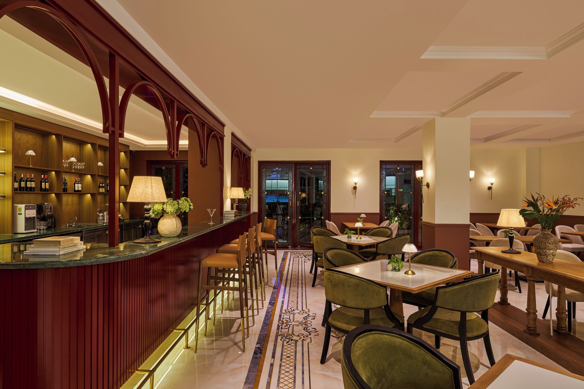Eine Bar mit Theke, Barhocker und einer Sitzgelegenheit mit Tischen und Stühlen.