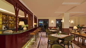 Eine Bar mit Theke, Barhocker und einer Sitzgelegenheit mit Tischen und Stühlen.