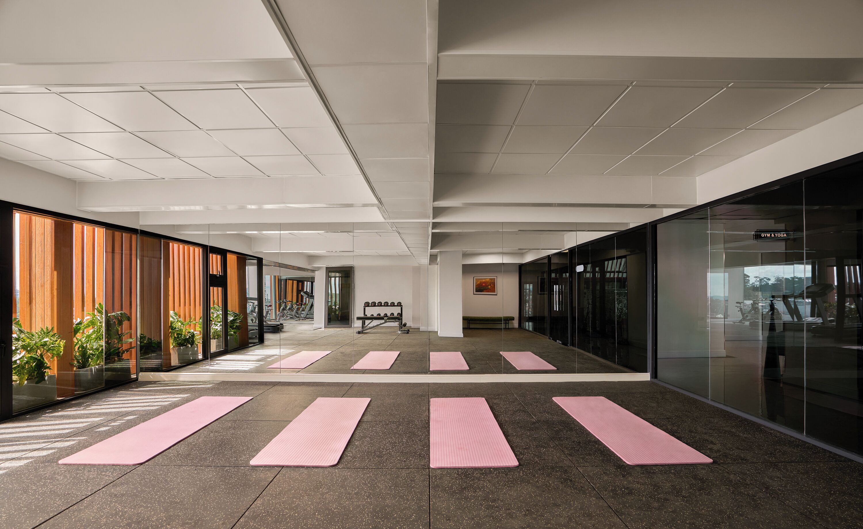 A modern indoor gym with exercise equipment, mirrored walls, and a clean, spacious layout.