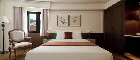 Habitación de hotel con una cama grande, una silla, un escritorio, una lámpara y vistas al exterior.