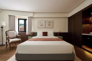 A hotel room with a large bed, a chair, a desk, a lamp, and a view of the outside.