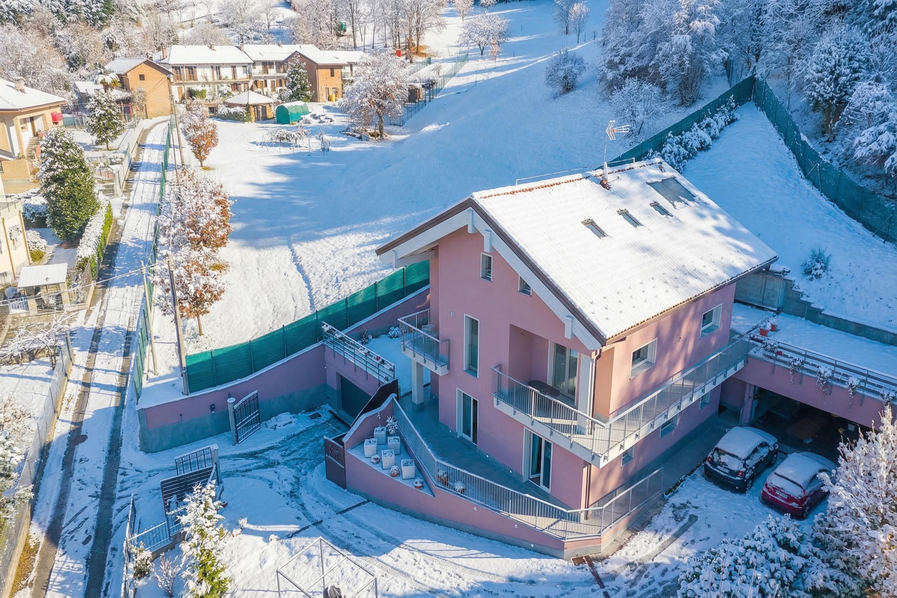 A two-story house with a balcony, a garage, and a snow-covered yard.