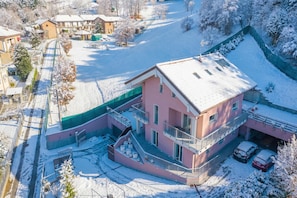 Ein zweistöckiges Haus mit Balkon, Garage und einem schnee bedeckten Garten.