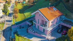 A multi-story pink building with a red roof, a balcony, and a garage with two cars. - Appartamento Girasole with Terrace, Torino, Italy (Torino)