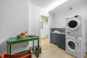 A compact kitchen with a washing machine, a dining table with chairs, and a hallway leading to another room. - Appartamento Girasole with Terrace, Torino, Italy (Torino)
