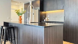 Eine moderne Küche mit einer zentralen Kochinsel, dunklen Holfschränken und einer Vase mit Blumen.