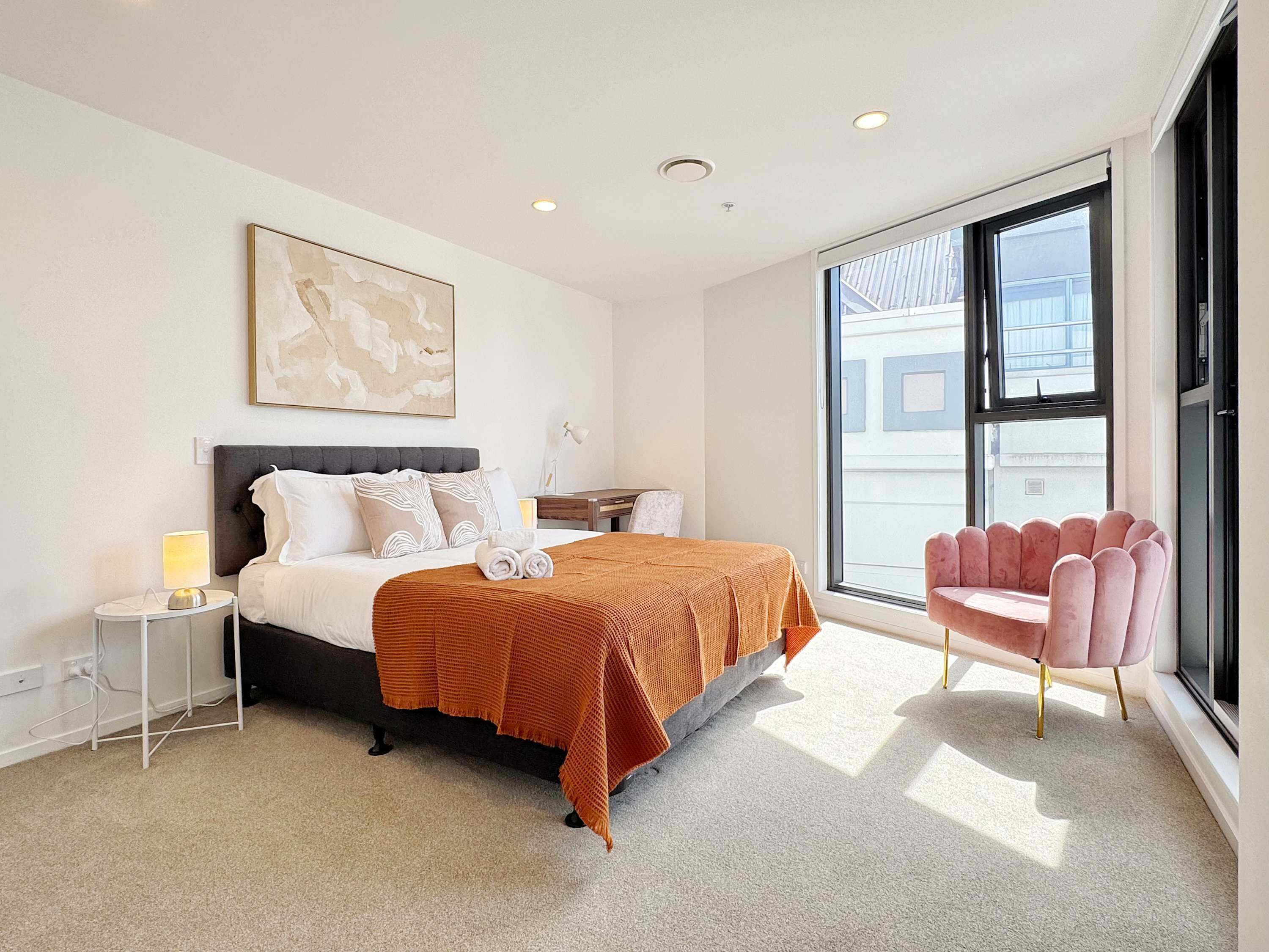 Een moderne hotelkamer met een groot bed, een nachtkastje, een bureau, een stoel en een groot raam.
