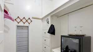 Une pièce compacte comprenant un coin cuisine, une petite télévision et une fenêtre avec des stores.