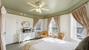 Une chambre à coucher comprenant un lit, une chaise, une commode, un miroir et un ventilateur de plafond.