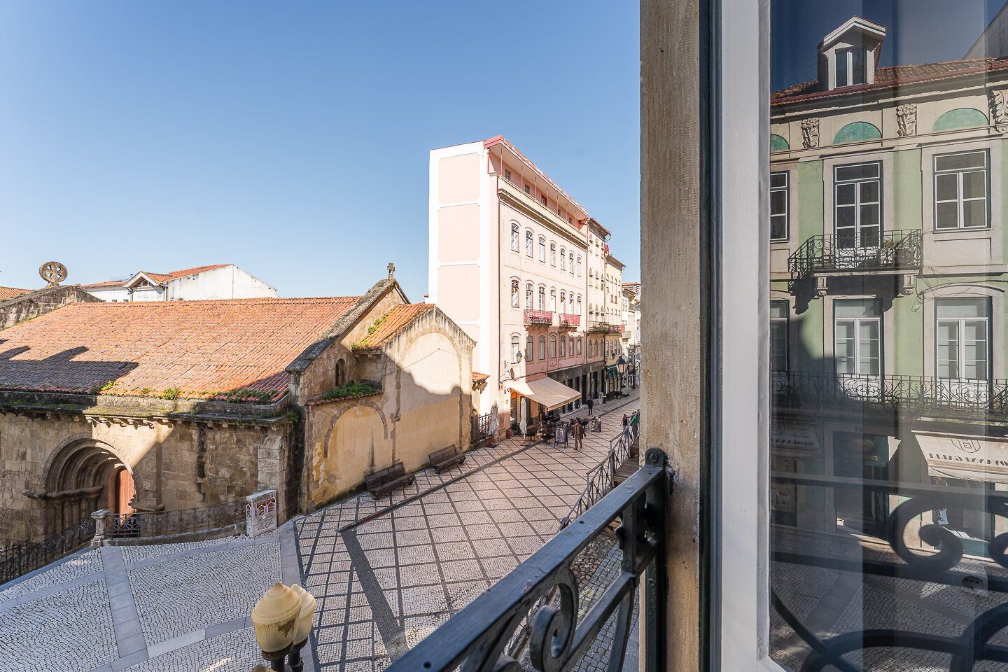 Une vue d’une place historique, avec ses pavés, ses bâtiments traditionnels et un ciel bleu dégagé.