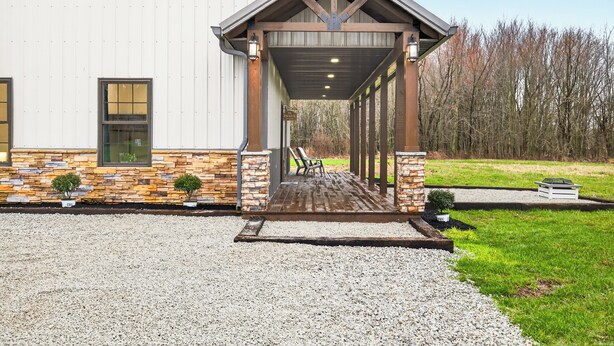 A covered outdoor area with a gravel path leading to a building with stone accents and a wooden pergola. - Modern Retreat w/ Private Hot Tub & Bunk Room (Jasonville)