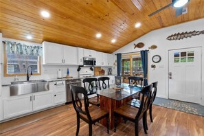 A modern kitchen with white cabinets, a stainless steel sink, and a wooden dining table with chairs.