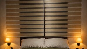 A bed with a green bedspread, two bedside lamps, and a wall with horizontal blinds. - Rancho Ajaw - Ajaw Kún Siuite Premium Hut 🌿 (Leona Vicario)