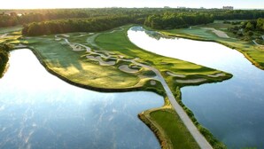 Campo de golf con obstáculos acuáticos y un camino despejado.