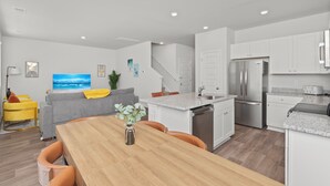 Una cocina moderna con armarios blancos, un refrigerador de acero inoxidable y un lavavajillas empotrado.