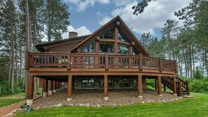 A large log cabin with a balcony, surrounded by a forest. - Otter Point Lodge - 4BR, 3BA 1100ft water frontage log home w/ 2 docks & firepit (Land O' Lakes)