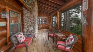 A log cabin with a stone pillar, wooden benches, and a sign reading 'The Bailey's.' - Otter Point Lodge - 4BR, 3BA 1100ft water frontage log home w/ 2 docks & firepit (Land O' Lakes)