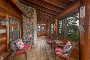 A log cabin with a stone pillar, wooden benches, and a sign reading 'The Bailey's.'