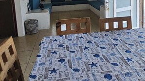 A room with a bed, a sofa, a ceiling fan, a window with curtains, and a door.