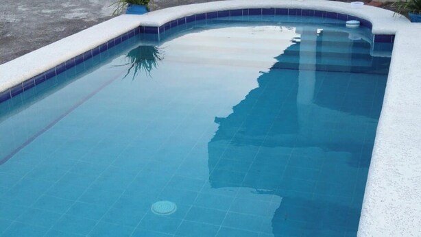 A rectangular swimming pool with a tiled edge and a circular drain in the center.