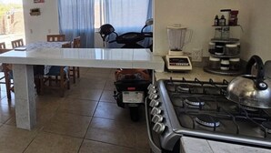 A kitchen with a gas stove, a blender, and a motorcycle in the background.