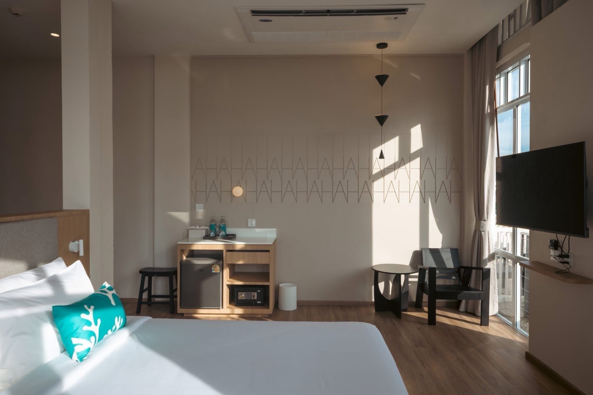 A hotel room with a bed, a desk, a chair, a TV, and a window.