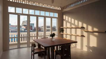 Una habitación con un ventanal grande, ventilador de techo y una mesa con sillas.
