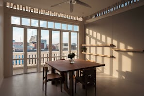 Una habitación con un ventanal grande, ventilador de techo y una mesa con sillas.