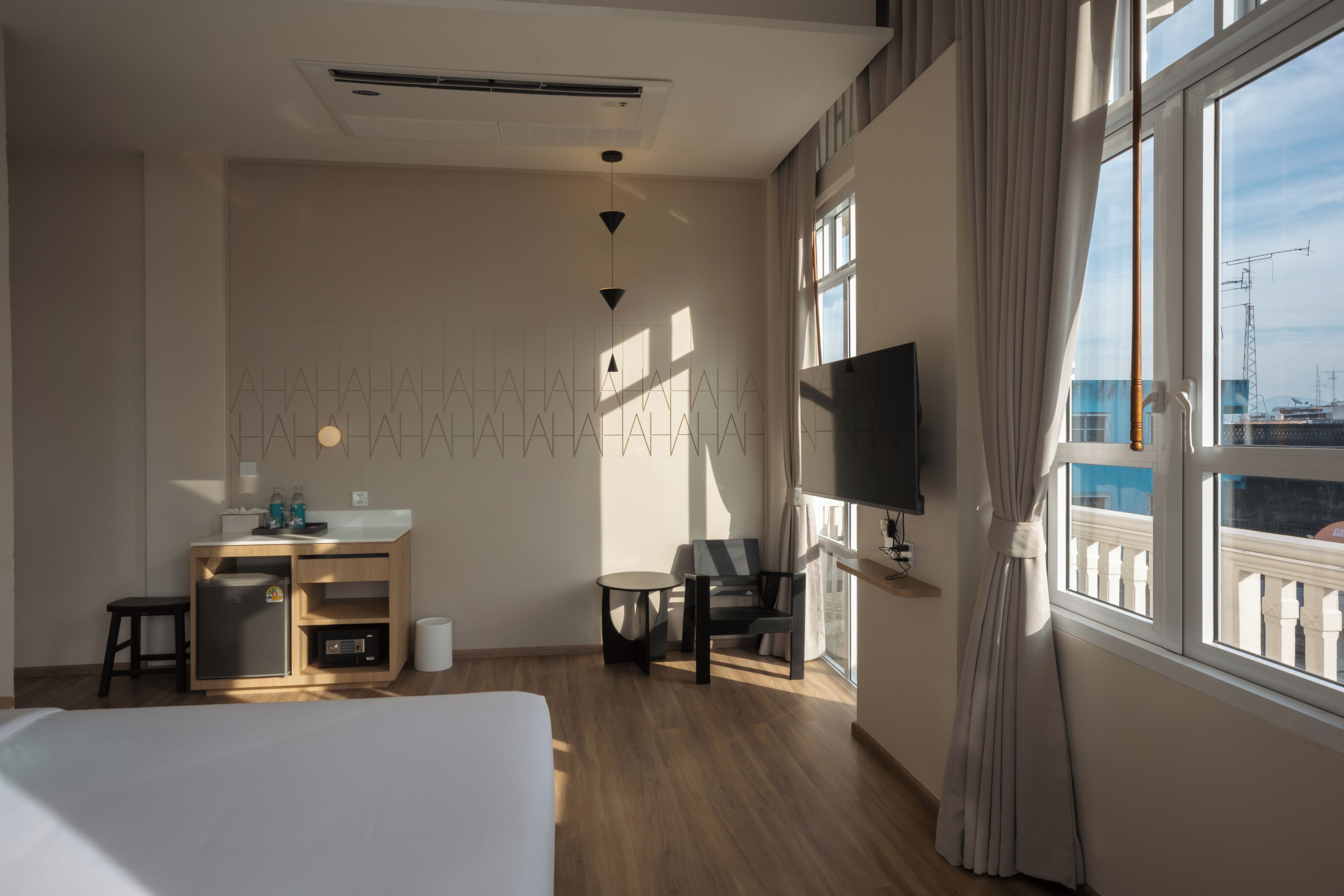 Una habitación de hotel con cama, escritorio con computadora, silla, televisor y ventana con vista a la ciudad.