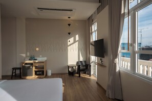 Een hotelkamer met een bed, een bureau met een computer, een stoel, een televisie en een raam met uitzicht op de stad.