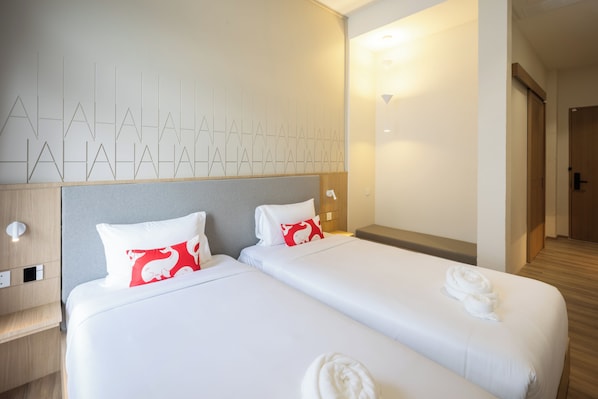 Habitación de hotel con dos camas, cabecero de madera, pared con diseños geométricos y puerta que da a otra habitación.