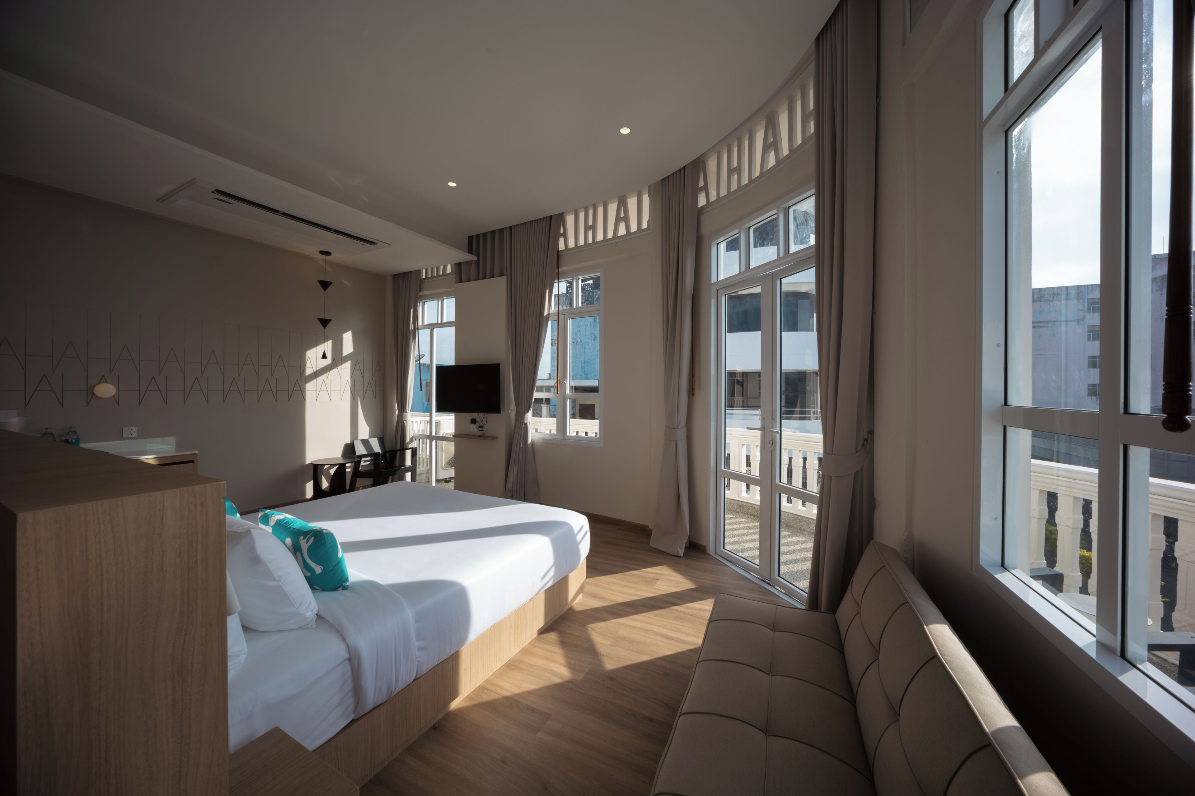 Habitación de hotel con una cama grande, televisión, balcón con vistas y suelo de madera.