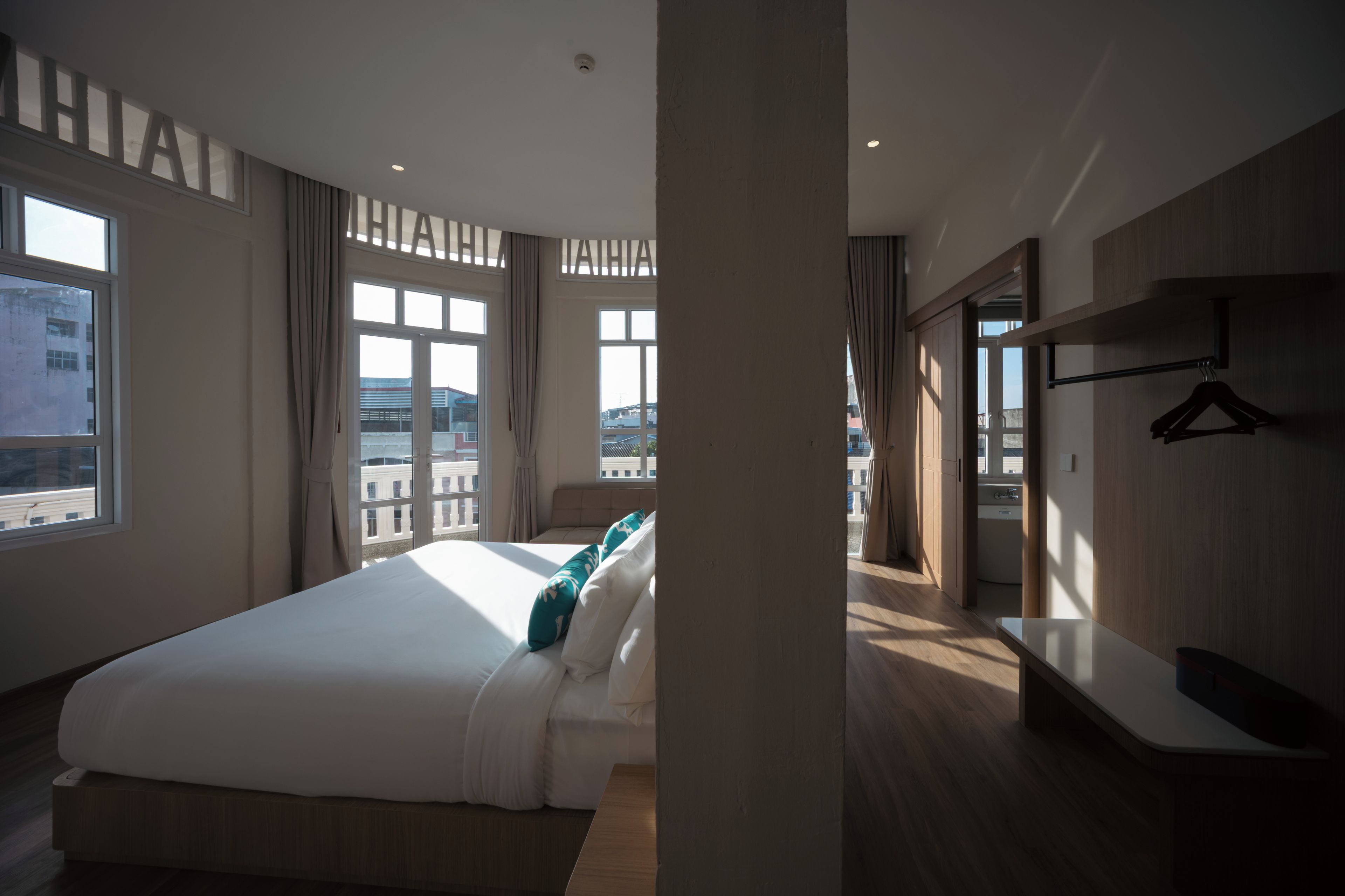 Ein Hotelzimmer mit einem großen Bett, einem Nachttisch, einem Kleiderschrank und Blick auf die Stadt.