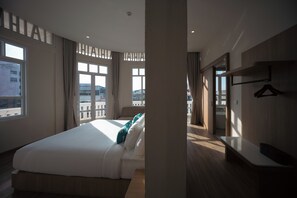 Een hotelkamer met een groot bed, een nachtkastje, een kledingkast en uitzicht op de stad.
