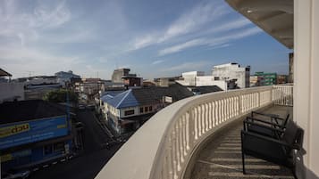 Un balcón con vistas a un paisaje urbano, incluyendo edificios y un cielo despejado.