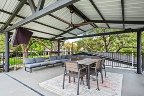 An outdoor patio with a covered seating area, a dining table, and chairs. - Lake Austin Bungalow | Private Dock + Swim Off the Dock (Austin)