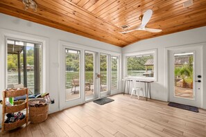 A spacious room with a wooden ceiling, large windows, and a view of a lake.