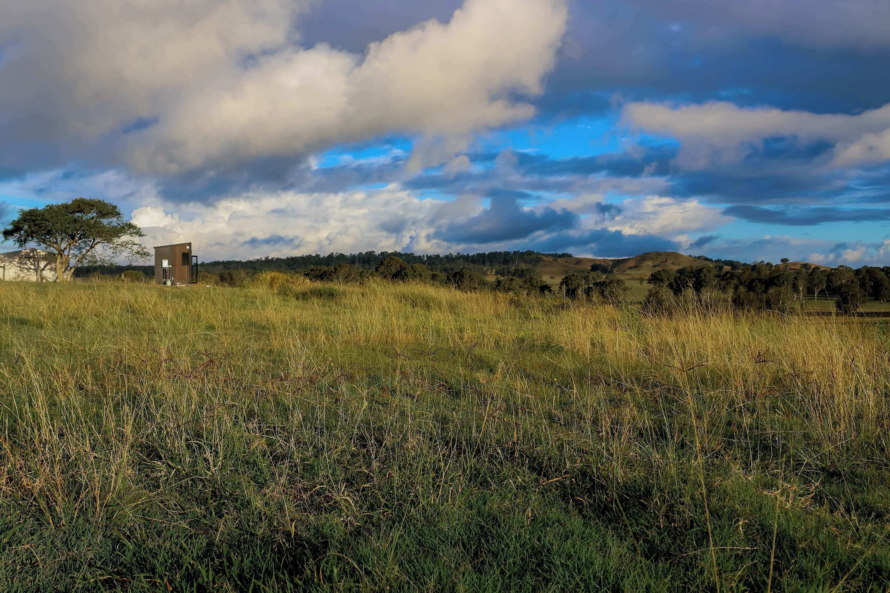 A grassy field with a small, isolated structure.