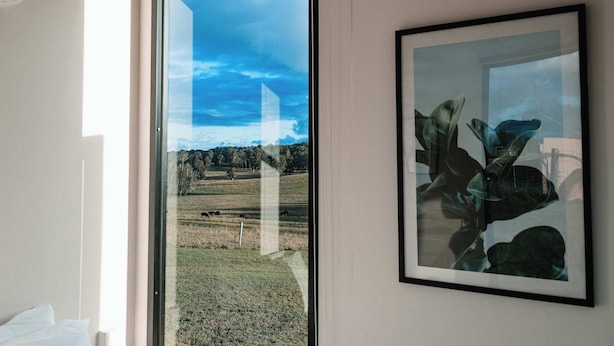 A room with a large window, a framed artwork, and a bed. - Hills and Herds by Tiny Away (Shannon Brook)