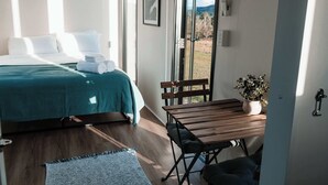 A bedroom with a bed, a wooden table, a bench, and a potted plant. - Hills and Herds by Tiny Away (Shannon Brook)