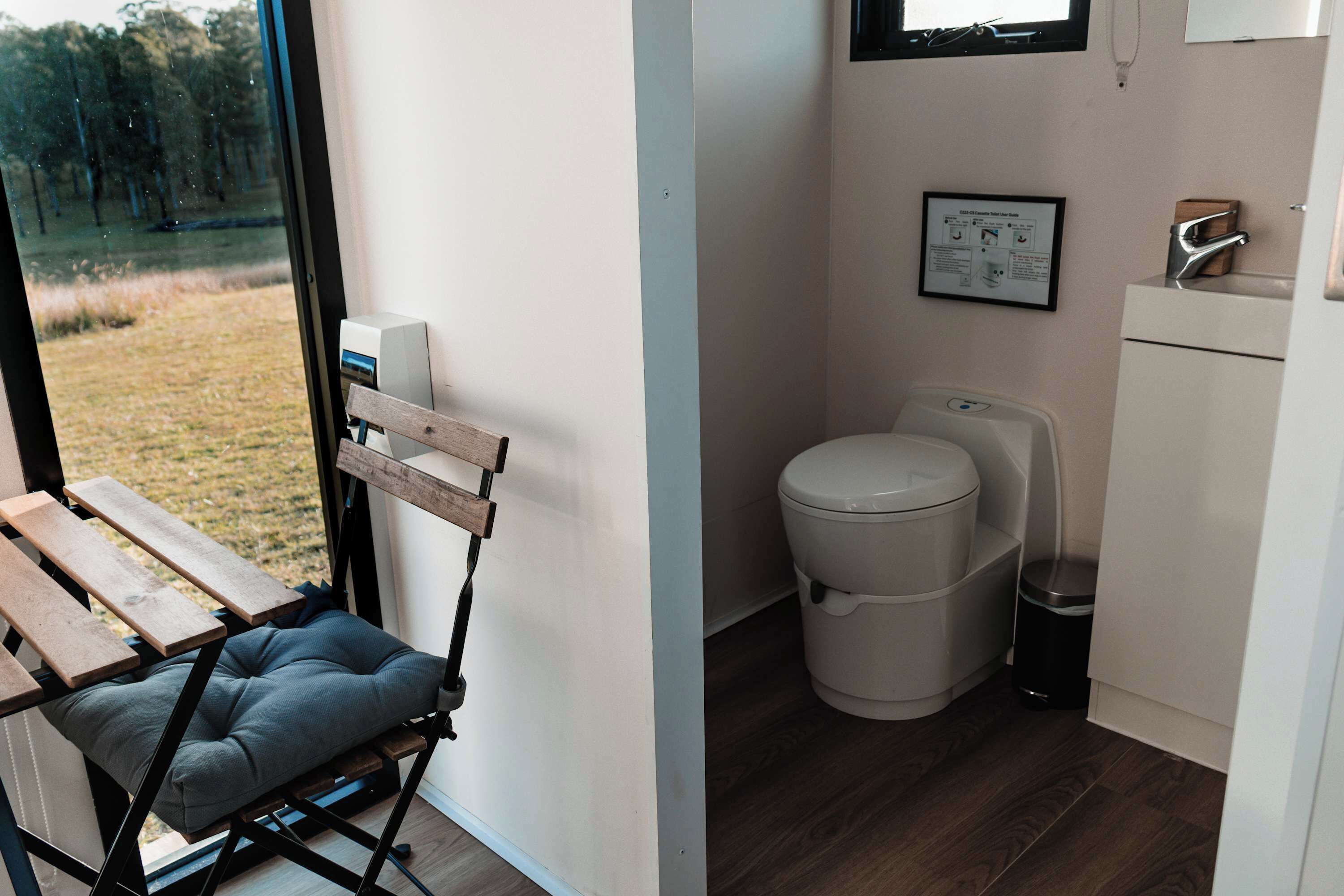 A room with a wooden bench and cushion, a toilet, and a sink.