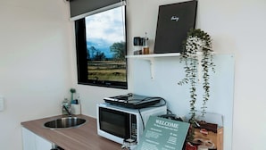 A compact kitchenette with a microwave, sink, and a welcome sign. - Hills and Herds by Tiny Away (Shannon Brook)