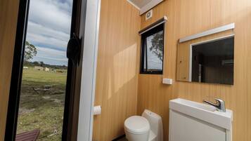 A compact bathroom with a toilet, sink, and mirror.