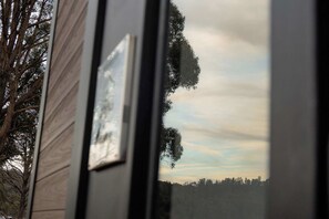 A window with a view of trees and a cloudy sky.