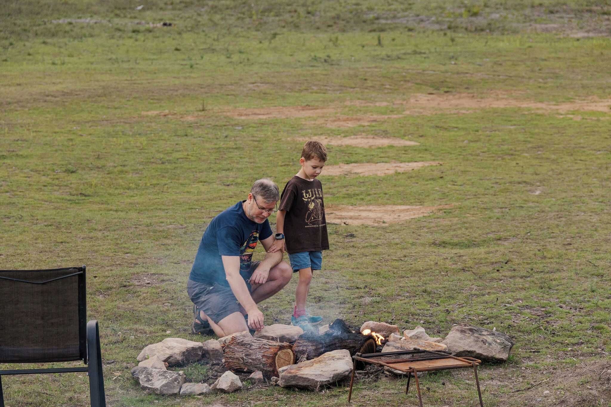 An outdoor setting with a fire pit, rocks, and a chair.